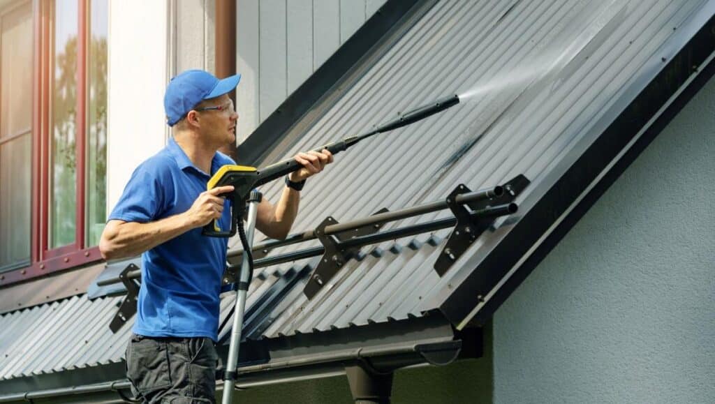 Metal roof benefits – worker water blasting a metal roof